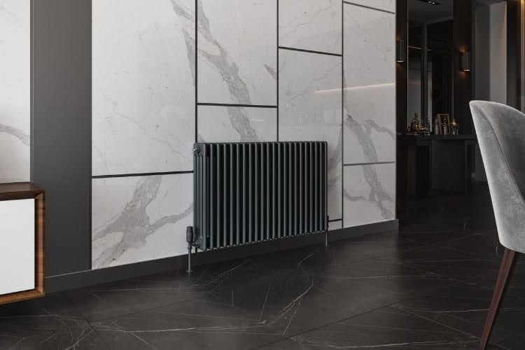 Modern black horizontal radiator installed against marble wall in contemporary living space.