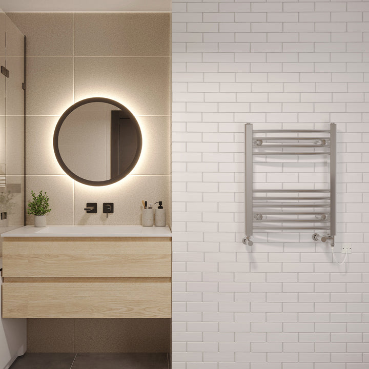 Zennor chrome dual fuel towel rail, 600mm x 500mm curved standard bathroom radiator, fitted in a modern bathroom next to a round mirror