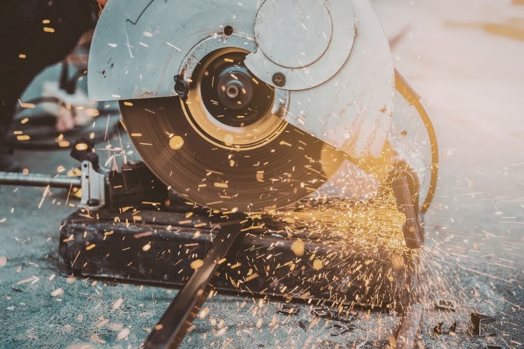 Metal cutting saw creating sparks while cutting steel pipe.