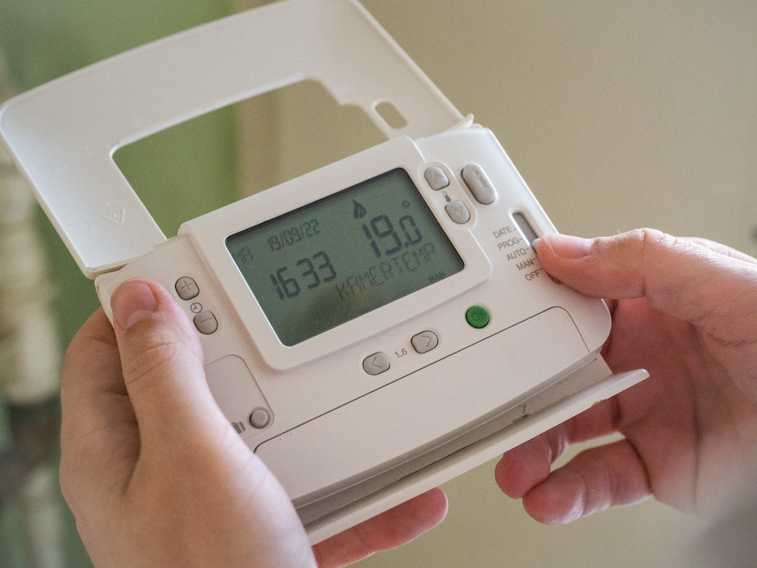 A close-up image of someone holding a thermostat