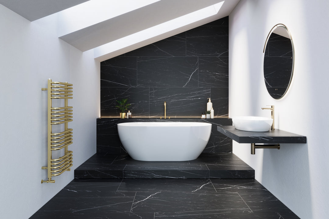 A white bathroom with black marbled flooring and a bathtub platform holding a freestanding white tub and a gold radiator.