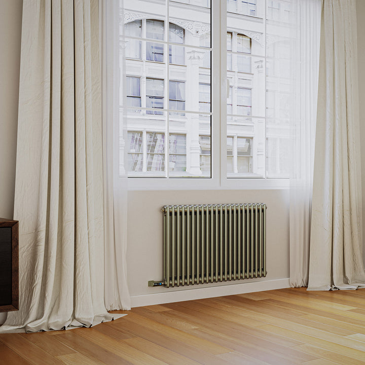 Anthracite vertical designer radiator installed beneath a tall window in a bright room with wooden flooring and light curtains.