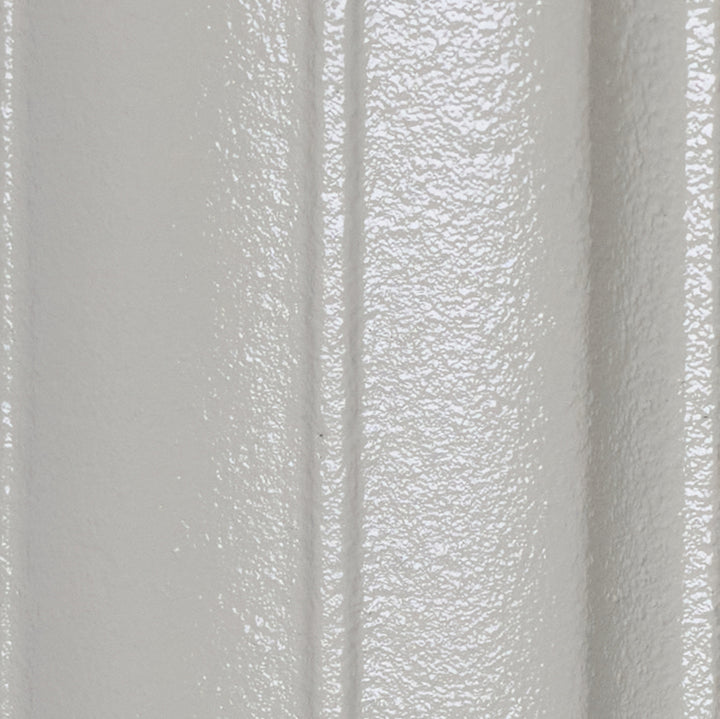 Close-up of the Pebble Grey cast iron radiator finish on a curved column surface.
